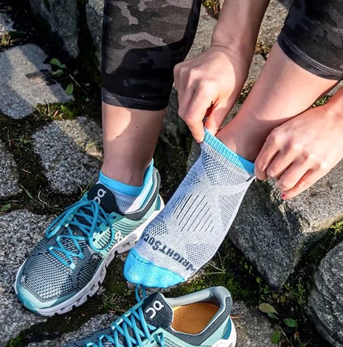 Person wearing blue athletic shoes and socks, sitting on a stone surface.
