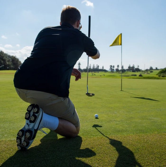 Golfer preparing to putt on a green with a yellow flag in the background