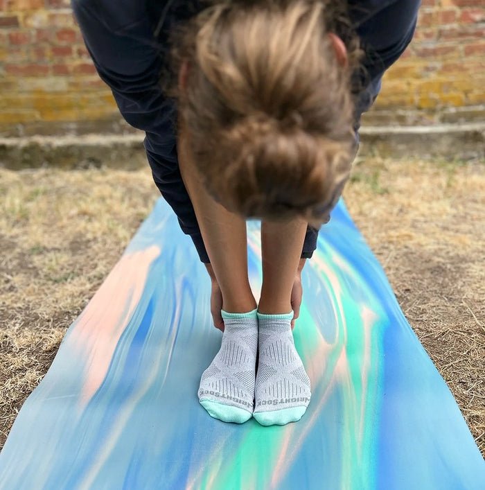 Person standing on a colorful fabric with another person bending over, possibly adjusting something.