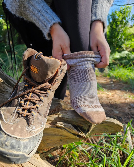 Woman putting on the best socks for sweaty feet during a hike